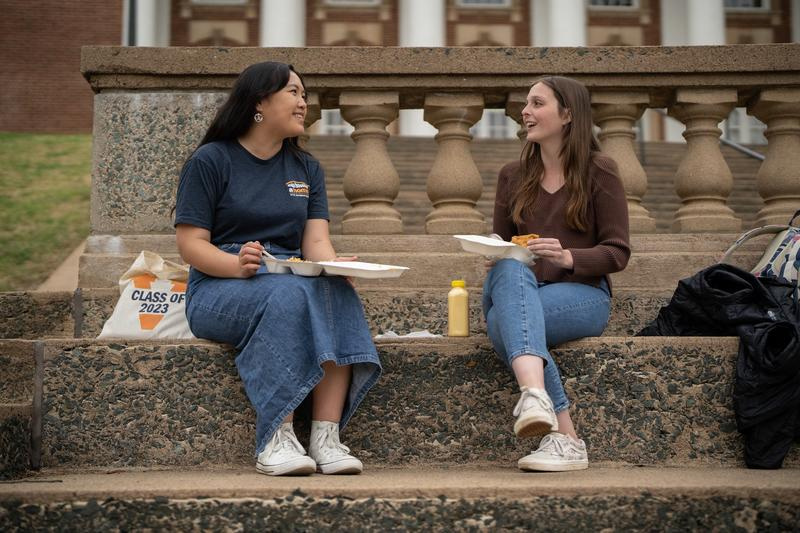 Students sitting on the stairs of building eating lunch